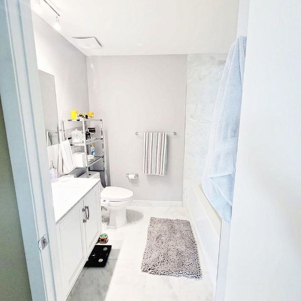 a bathroom with storage shelves over the toilet