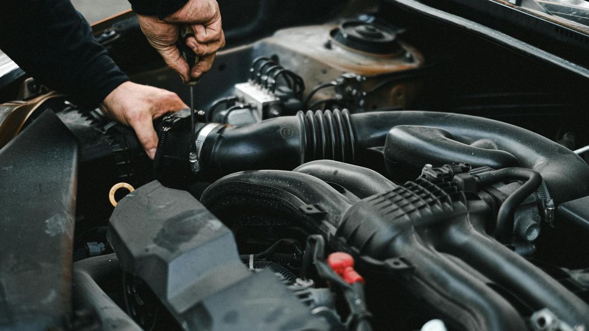 Person repairing car engine hose