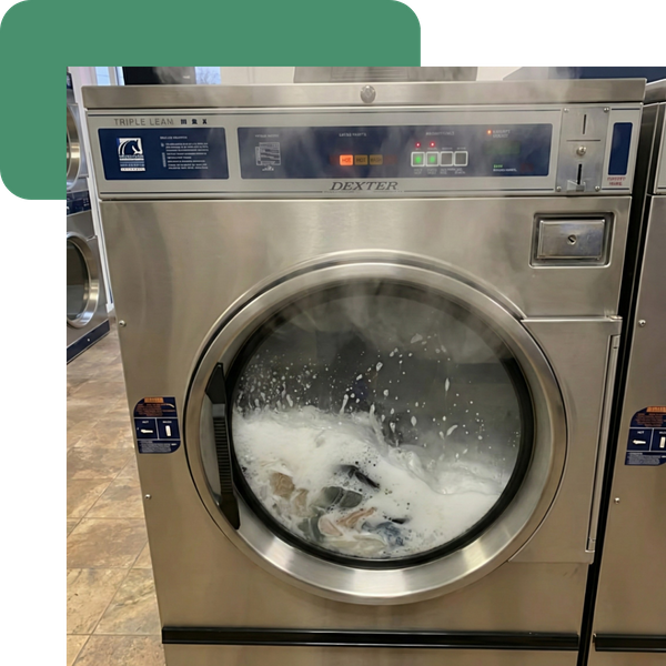 An action shot focusing on the washing process, showing soapy water churning vigorously and steam rising from a hot wash cycle to emphasize sanitization and temperature.