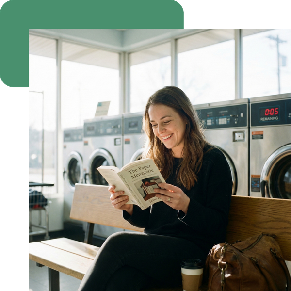 a woman happily reading a book waiting for her laundry to finish