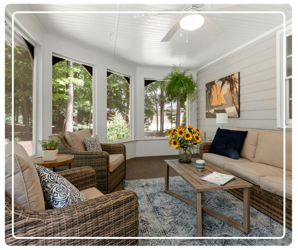 A custom sunroom and room addition in East Lake, FL featuring wicker furniture, panoramic views of a lush backyard, and a white plank ceiling.
