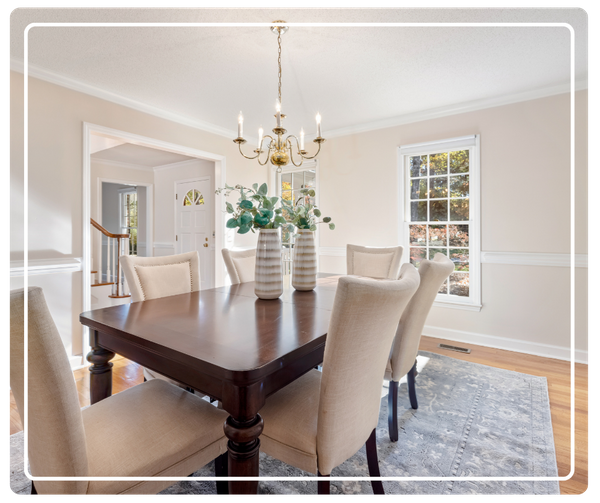 Elegant dining room renovation in Pinellas Park, FL with a dark wood table, traditional chandelier, and bright, sun-drenched windows.