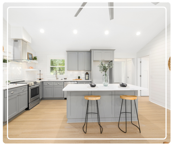 A bright, open-concept kitchen renovation in East Lake, FL showcasing gray shaker cabinets, light wood flooring, and modern shiplap wall accents.