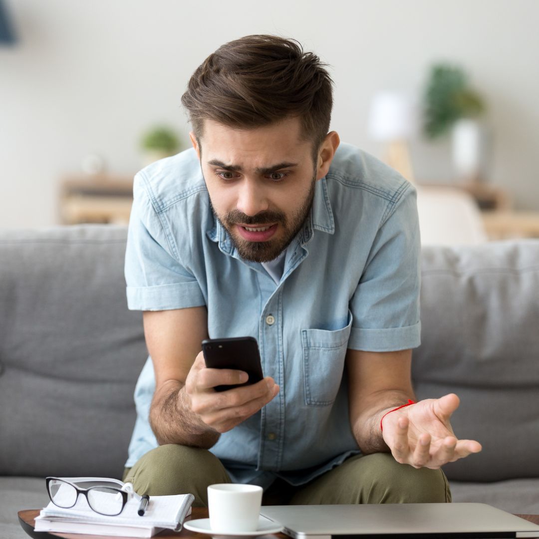 Man looking concerned while staring down at a cell phone. 