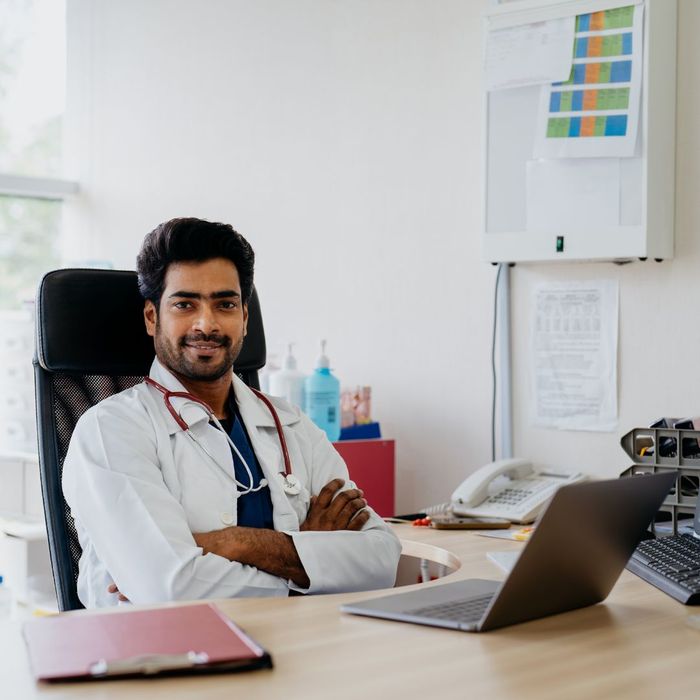 a doctor sitting in front of a laptop in his office