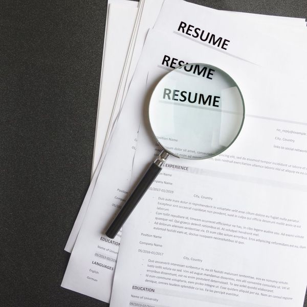 three resumes under a magnifying glass