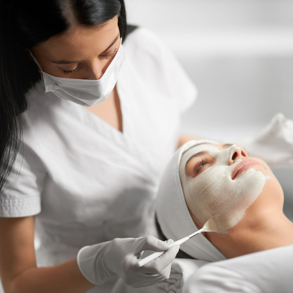 woman getting facial from cosmetologist