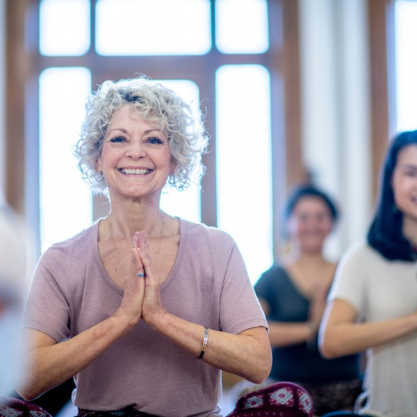an older woman smiling and doing yoga