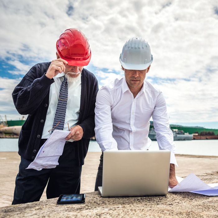Two men look at laptop at job site