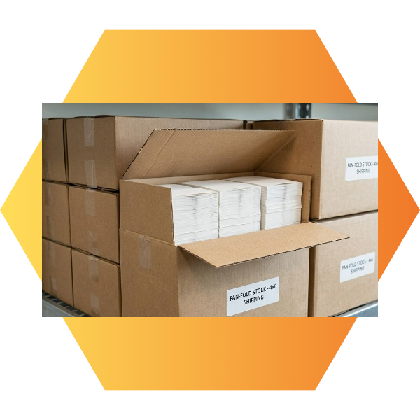 Neatly organized cardboard cartons on a warehouse shelf, with one box open showing compact stacks of fan-folded labels ready for storage.