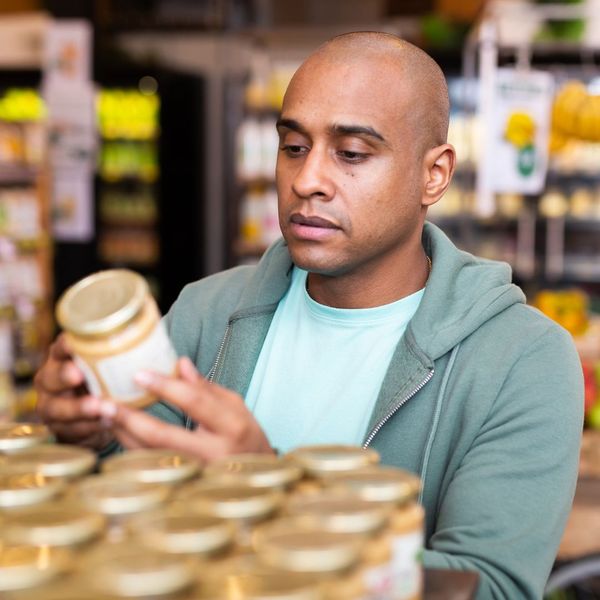 man reading label on jar in grocery store