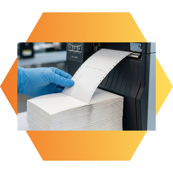 Close-up showing how a hand easily feeds a continuous stack of fan-folded labels into an industrial thermal printer, removing application curl.