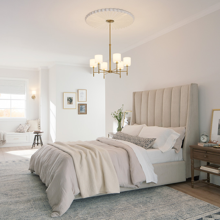 A warm, light colored bedroom with chandelier