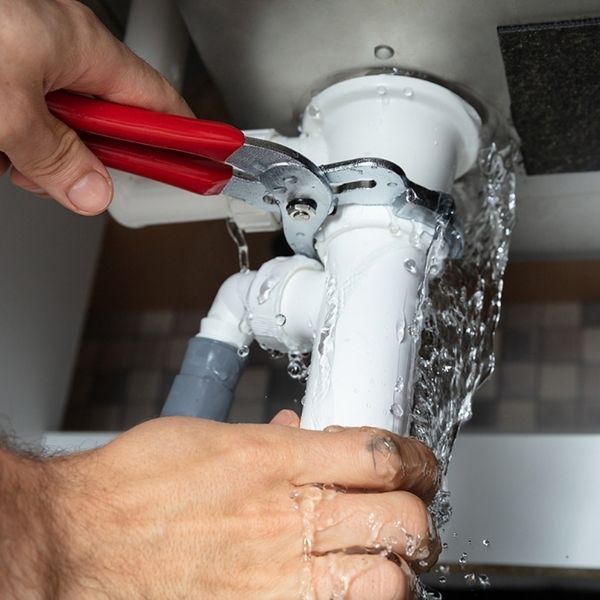 A plumber working on a pipe under sink