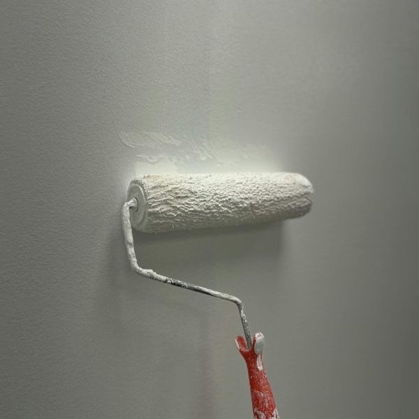 a close up of a paint roller on a wall painting the wall white