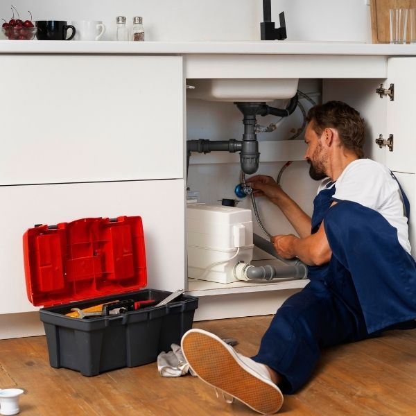 plumber working on the underneath of sink