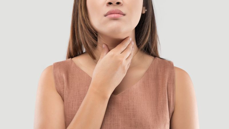 woman with hand on throat 
