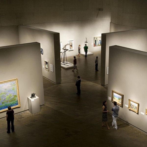 An overhead view of a busy art museum with several people walking through different sections of the gallery, viewing paintings and sculptures. An overhead view of a busy art museum with several people walking through different sections of the gallery, viewing paintings and sculptures.