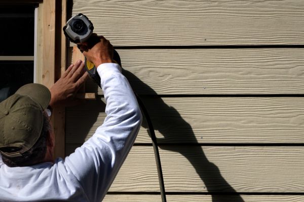 Man putting siding onto house Man putting siding onto house