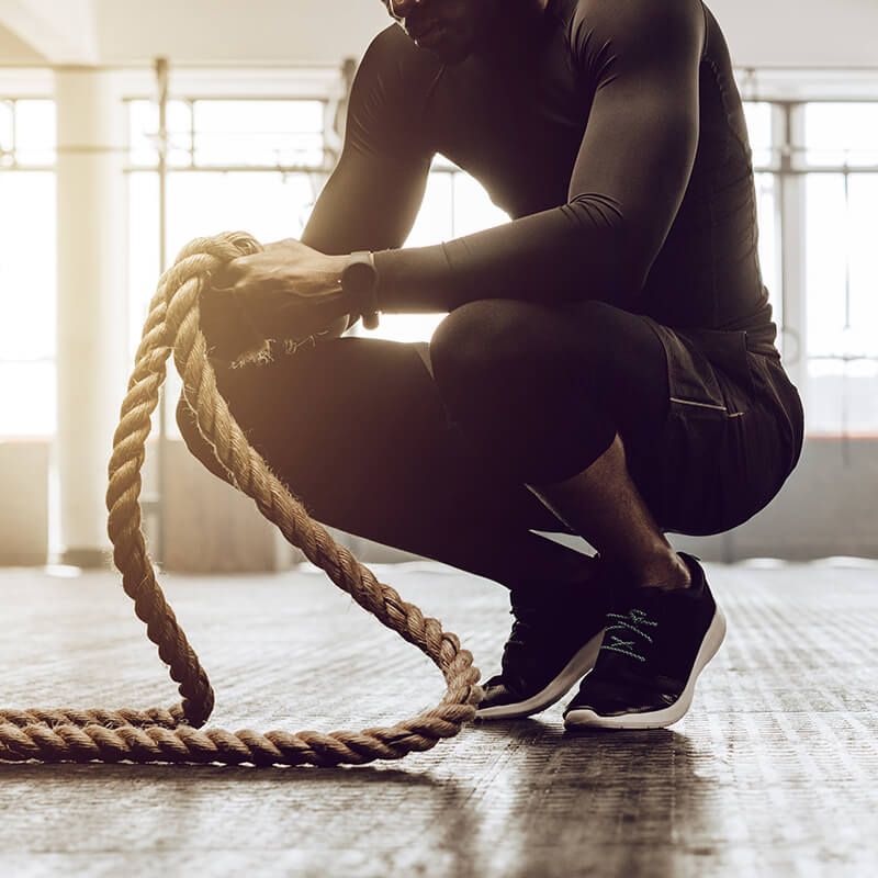 man kneeling with ropes