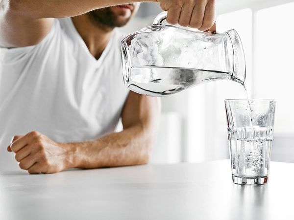 Man pouring water from pitcher into glass