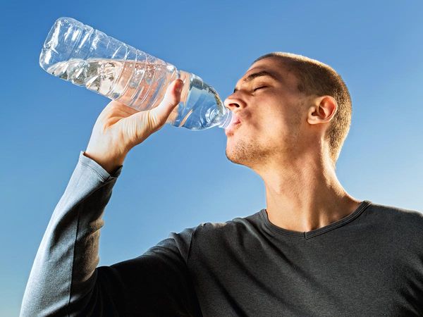 image of man drinking water from a clear plastic bottle