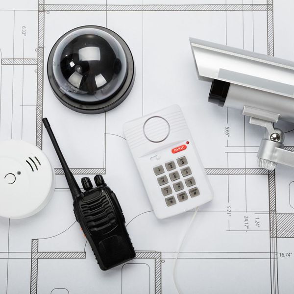 a blueprint with security cameras, a walkie talkie, a smoke detector and a security keypad on top