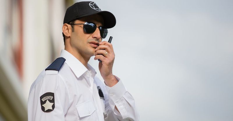 a man in a security uniform talking on a walkie talkie