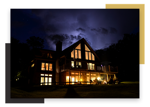 large lodge at night with backyard lighting