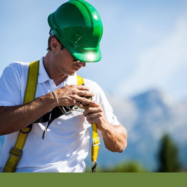 roofer putting on his harness to do work on a roof
