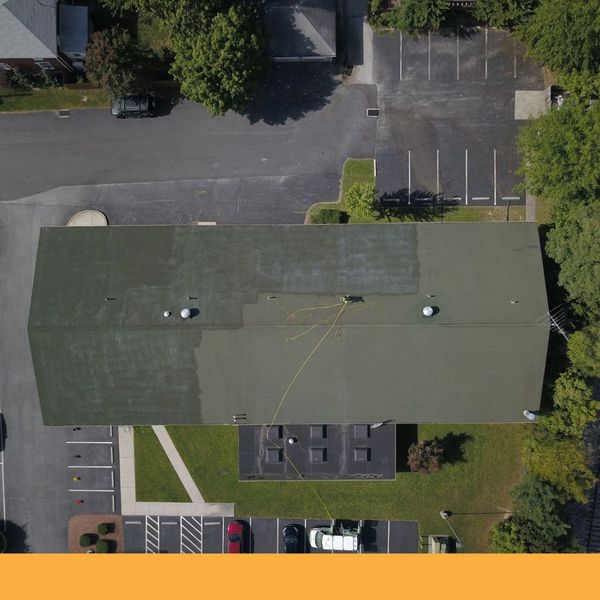 Aerial view of a commercial roof being cleaned, showing clean and dirty sections Aerial view of a commercial roof being cleaned, showing clean and dirty sections