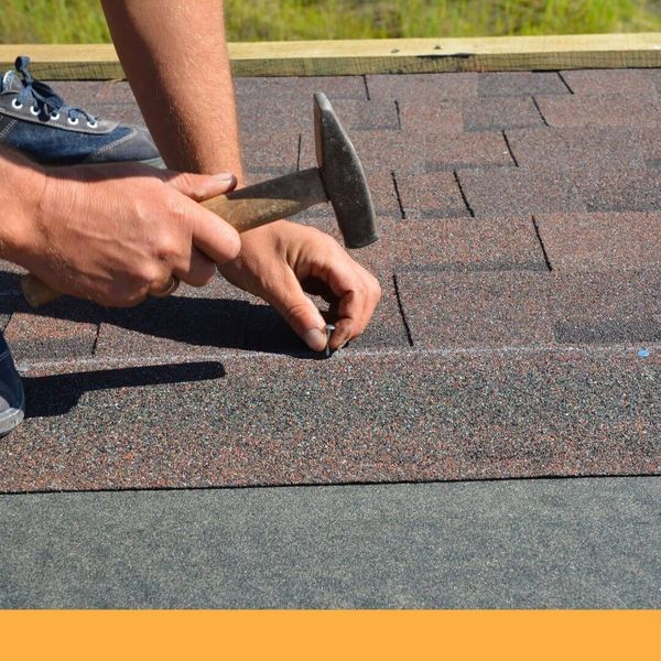 Roofer nailing down shingles
