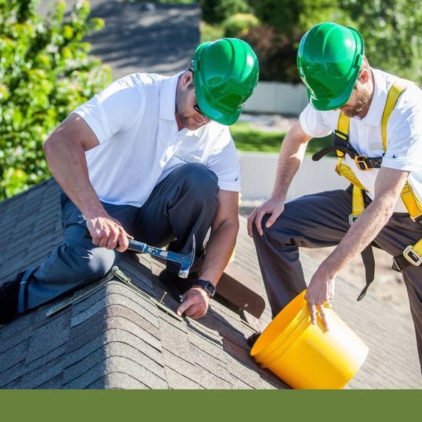 Two roofers hammering a nail into shingles