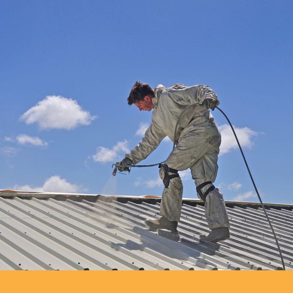 Man in protective suit spraying a roof. Man in protective suit spraying a roof.