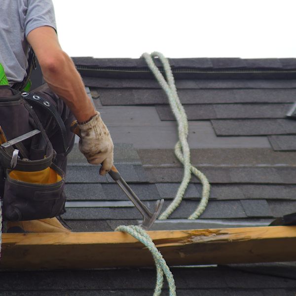 Man with hammer in hand as he stands on a roof under construction