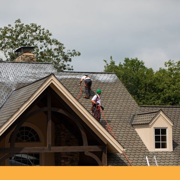 Two roof cleaner working on a complex residential roof with multiple dormers Two roof cleaner working on a complex residential roof with multiple dormers