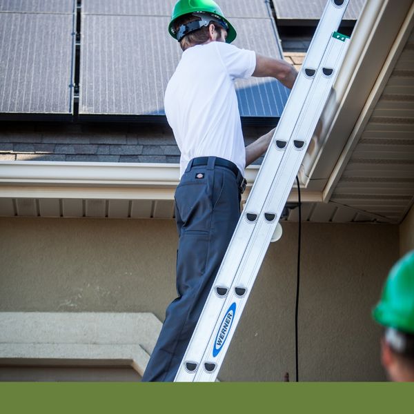 Man on ladder working on roof installation