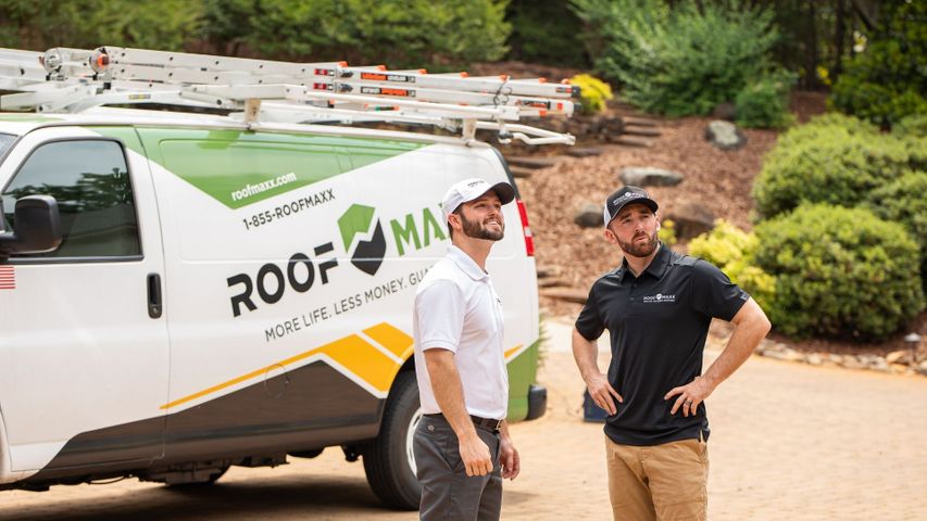 Guaranteed Roof employees standing in front of a Roof Maxx van Guaranteed Roof employees standing in front of a Roof Maxx van