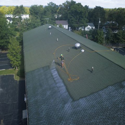 a person spraying soap on a roof Importance of Regular Roof Cleaning.jpg