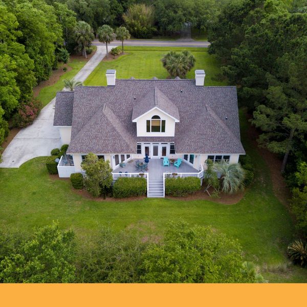 Aerial view of a large white house with a landscaped yard and long driveway Aerial view of a large white house with a landscaped yard and long driveway
