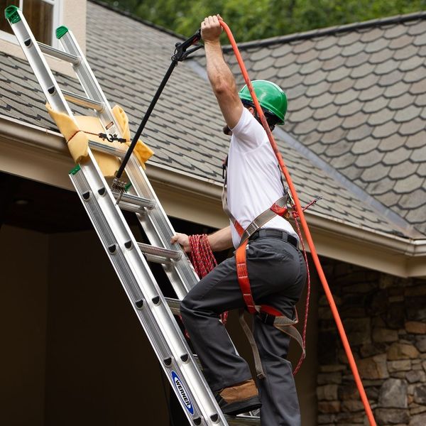 roofer climbing a ladder to a roof