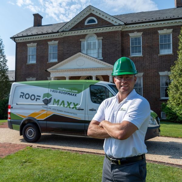Roof Maxx employee standing in front of van in front of a house