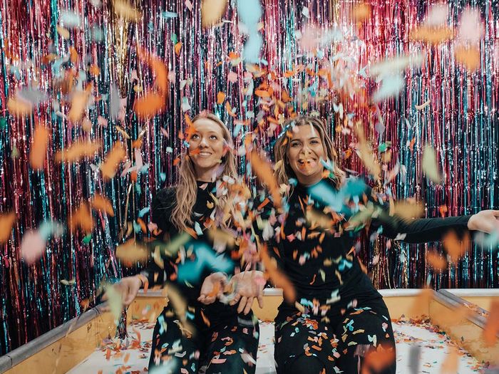 two girls taking a picture with confetti falling