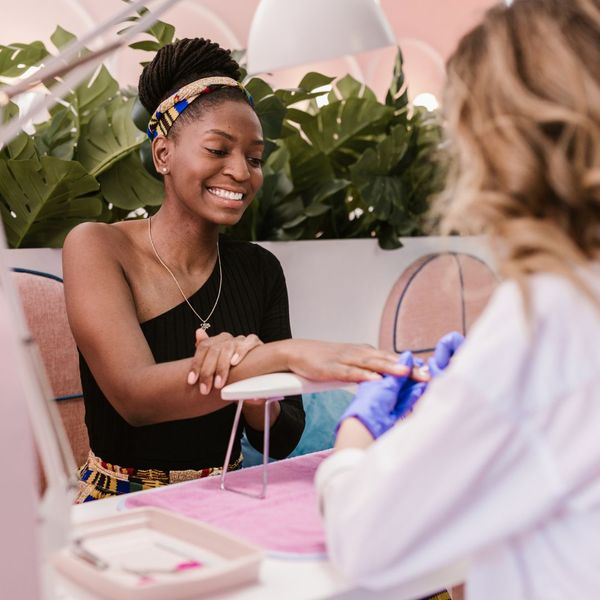 A woman smiling while getting a manicure