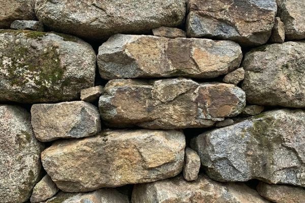Close-up detail of a rustic, dry-stacked natural granite boulder retaining wall.