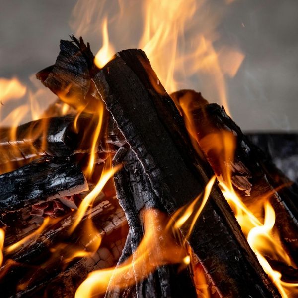 Close-up of a pile of neatly split firewood logs with an axe resting on top, suggesting wood splitting or delivery service.