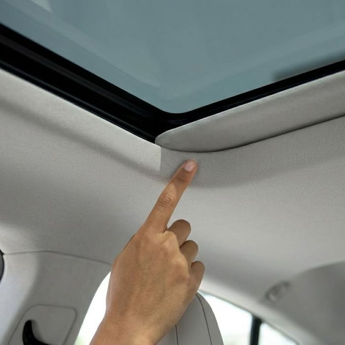 a hand pointing to the spotless, dry headliner near the clean sunroof seal
