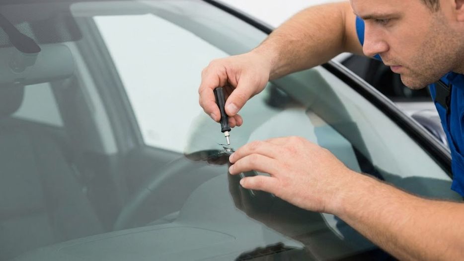A man repairing a small chip in a windshield