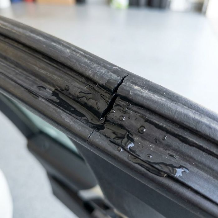 A close-up view of a cracked and leaking sunroof seal.