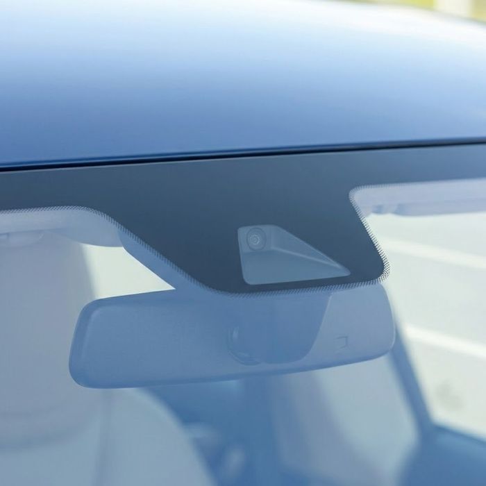 A subtle camera housing is mounted behind the rearview mirror on a flawless windshield.